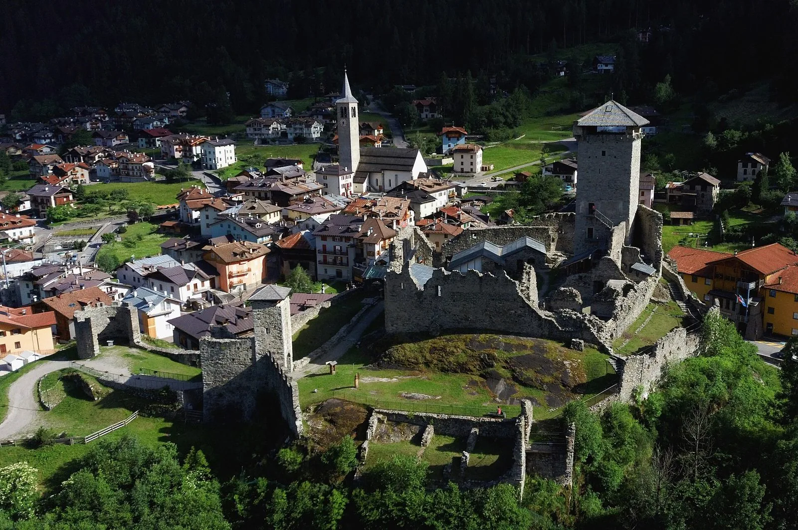Veduta aerea di Ossana con le rovine e la torre del Castello di San Michele, il campanile e le case del borgo